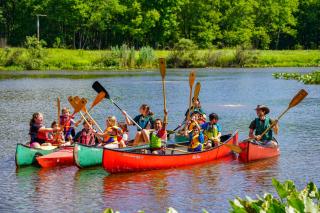 EEC Summer Camp Canoeing on the Pond group canoe photo with paddles in the air